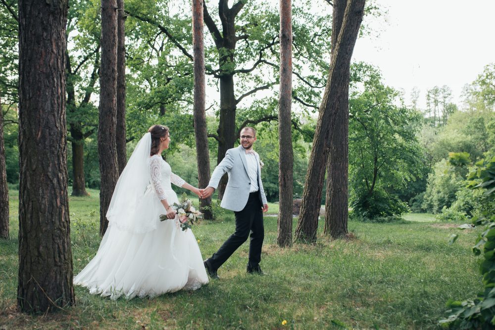 Bride and groom are walking in the woods on their wedding day