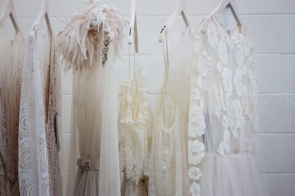 Wedding dresses hanging on rack in front of white wall