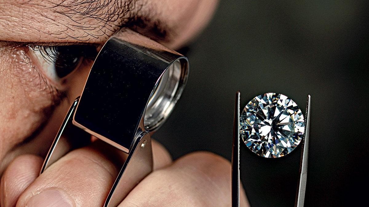 man looking at a diamond through magnifying glass