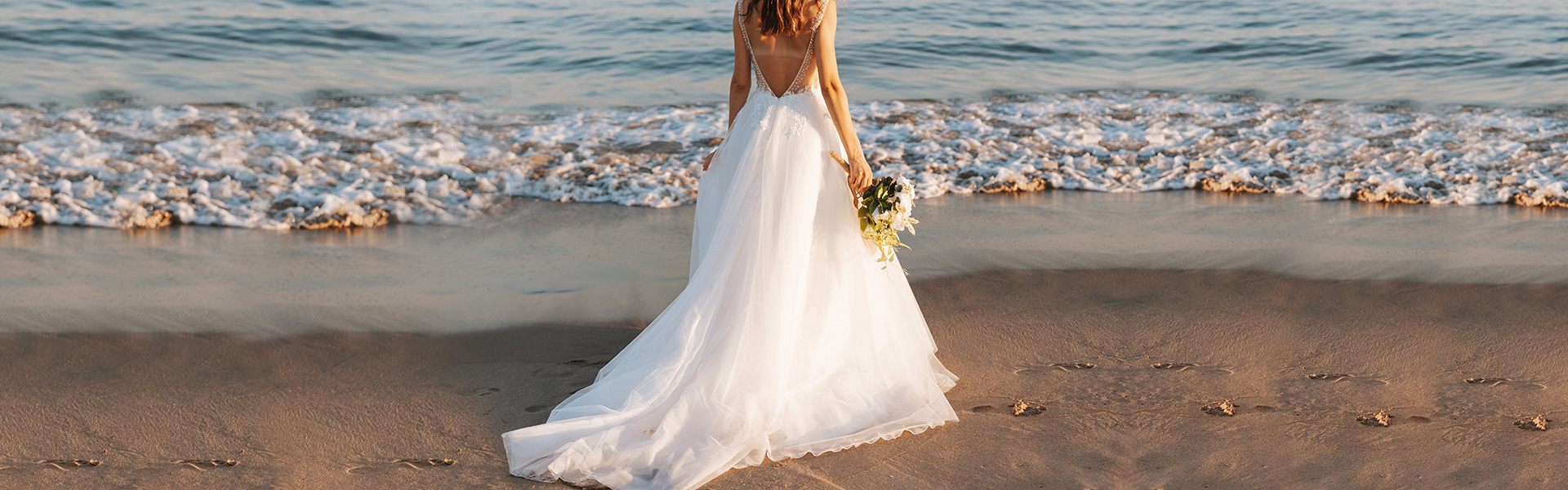 Bride in long dress looking out to the ocean