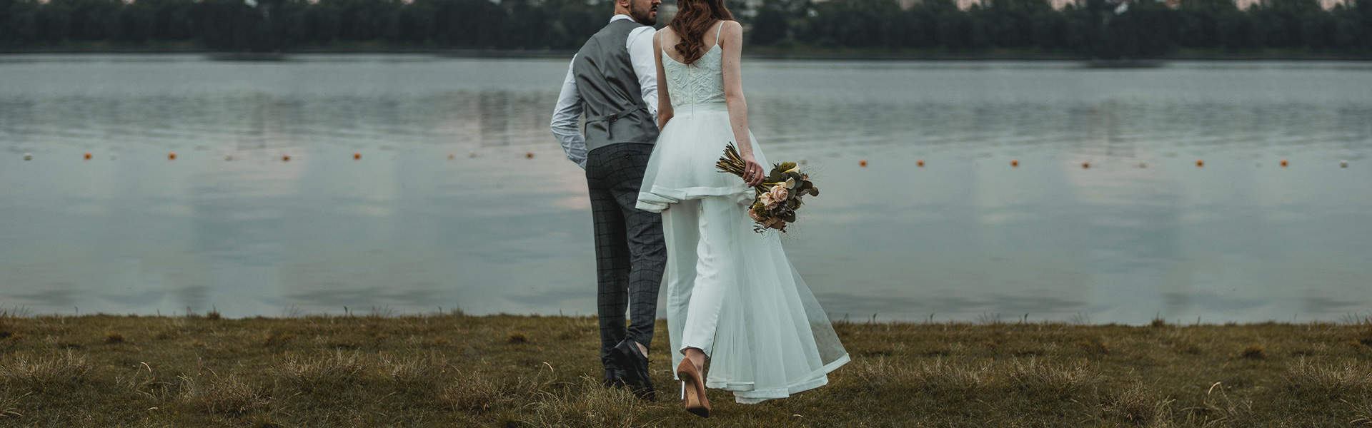 New bride and groom walk out to the lake shore to share a tender moment