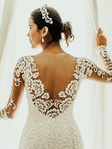 Gorgeous bride in long sleeved gown opening window