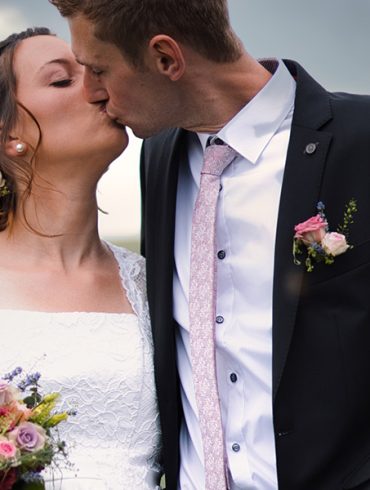 Bride and groom kiss in a stormy field