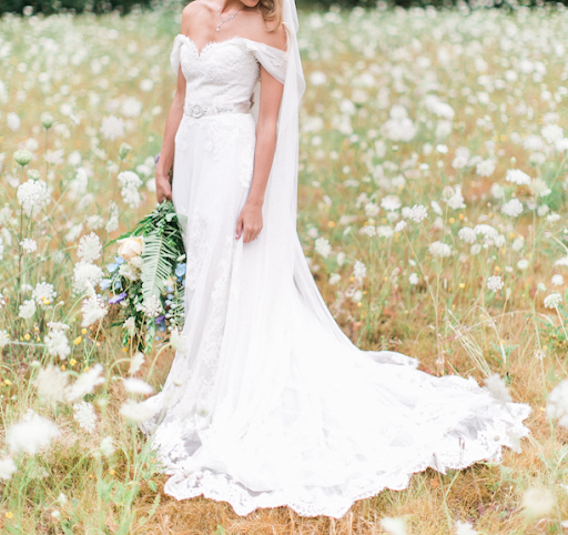 Bride in meadow showing off white dress