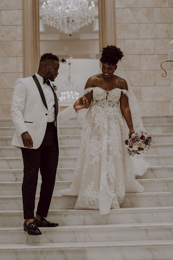 Bride and groom walk down stairs in stunning white clothes
