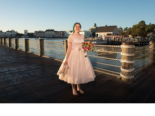 Bride standing near a water front in her short dress