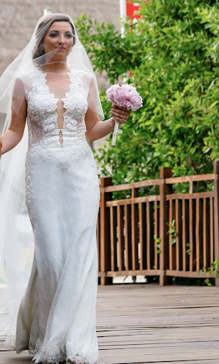 Bride walking across bridge with flowers in hand
