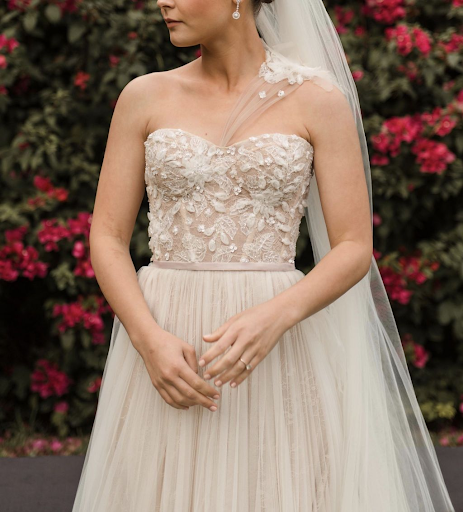 Bride in front of rose bush wearing a dress with a subtle strap