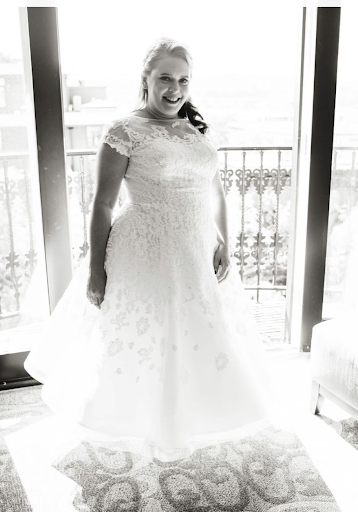 Bride showing off her dress near a window