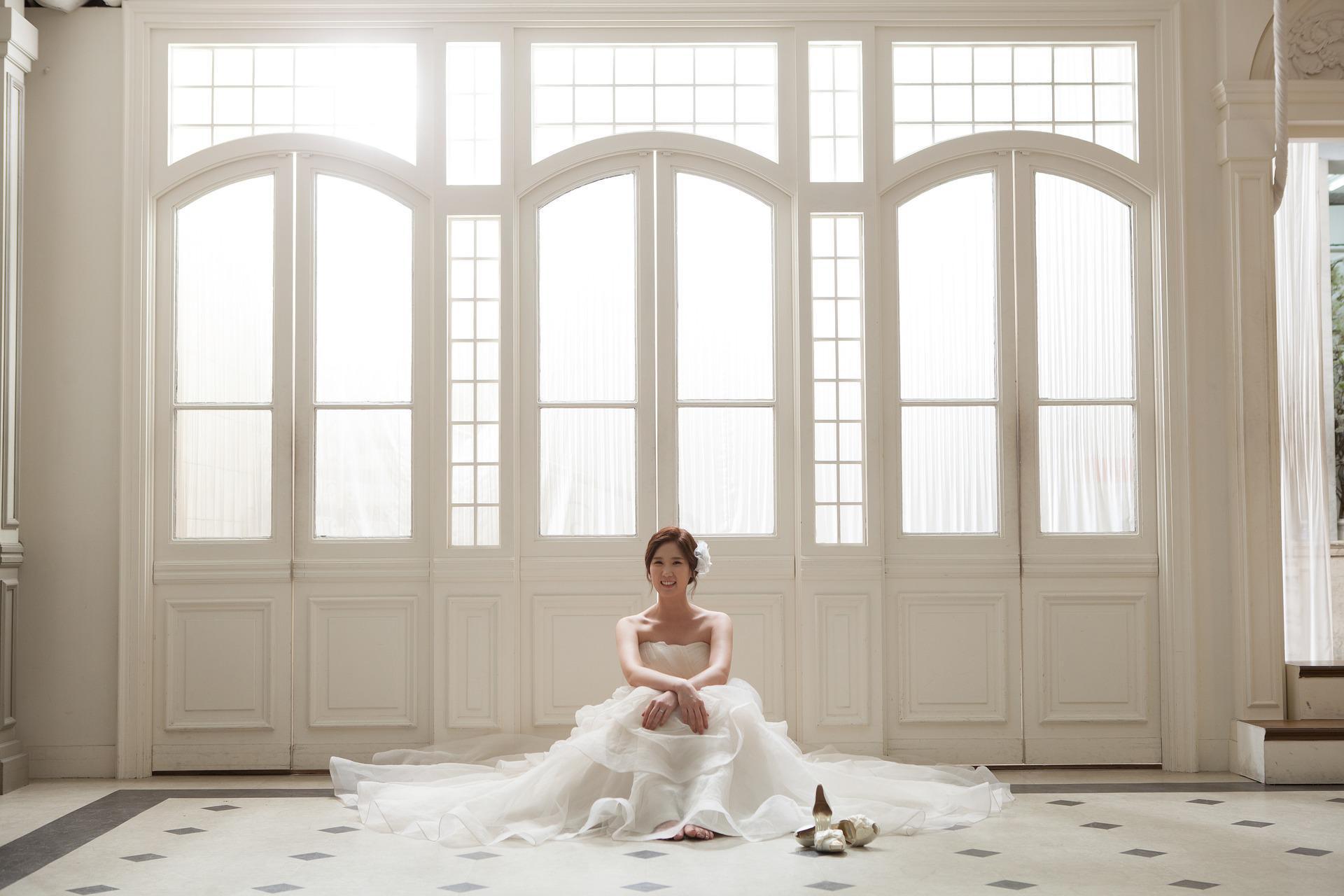 Recently married bride sitting on floor of venue in wedding dress
