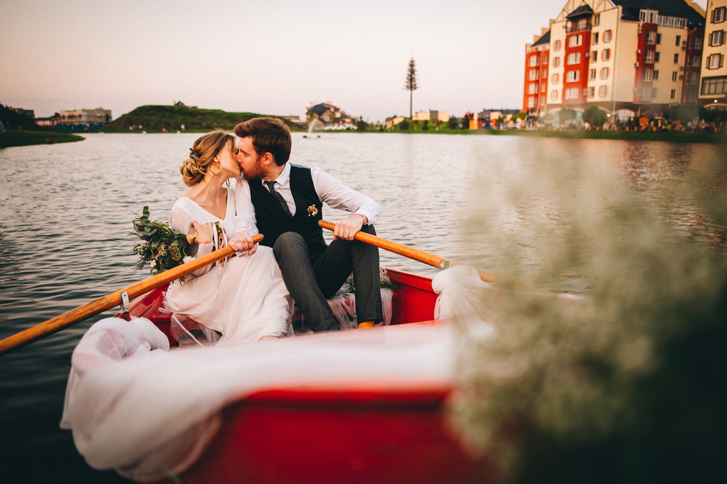 Bride and groom kissing on a rowboat