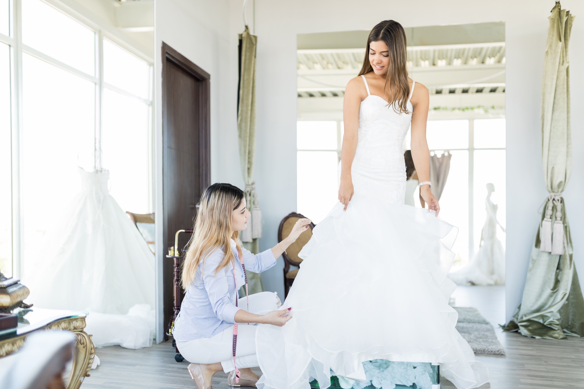 Seamstress adjusting a wedding gown on a bride