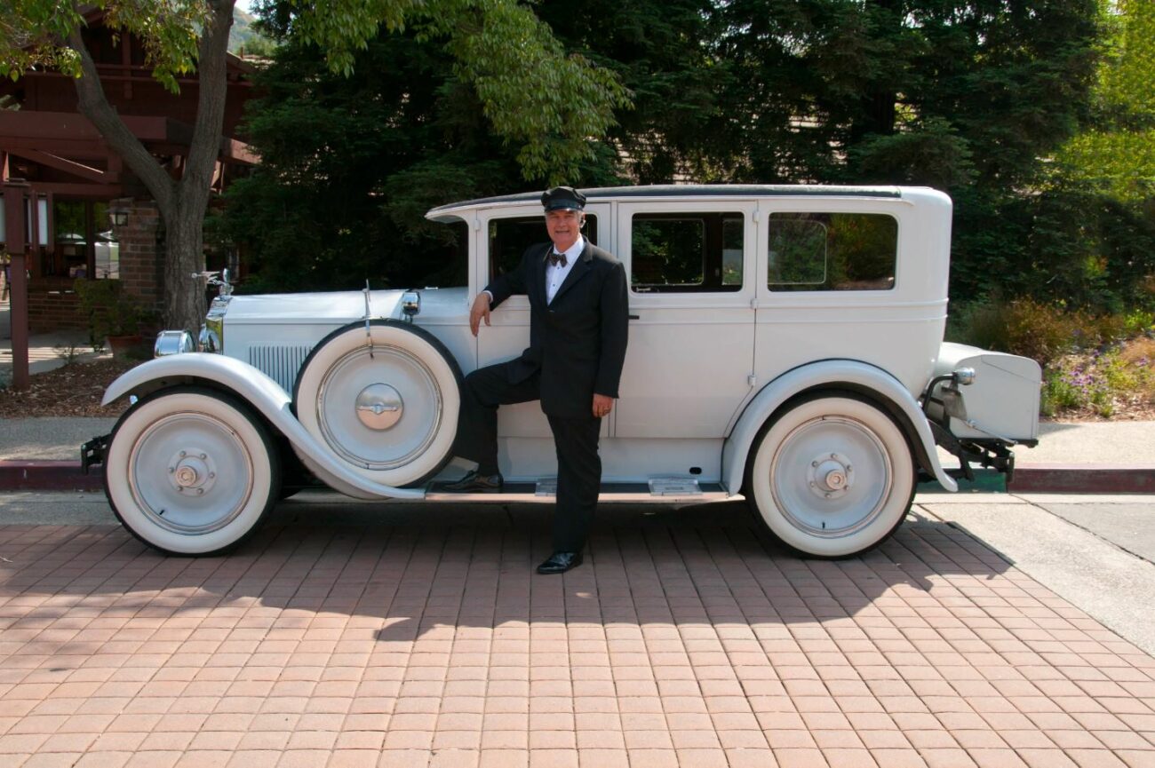 driver standing next to white vintage limo